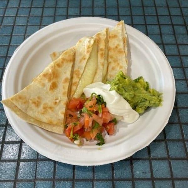 Cheese quesadilla slices with guacamole, sour cream, and pico de gallo on a white plate.